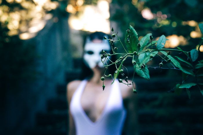 Woman in cat mask and white top with plant