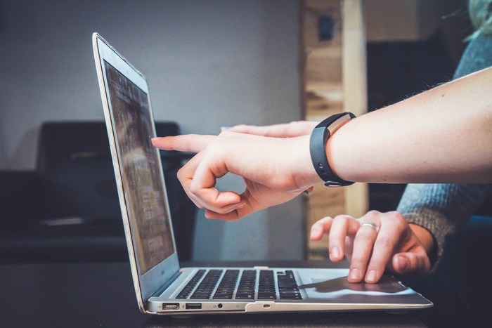 Hands pointing at a MacBook laptop screen