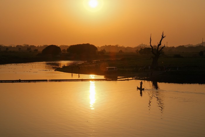 Sunset over a river in Myanmar with a fisherman in a boat