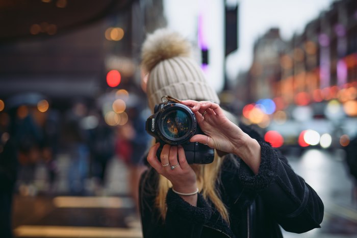 Woman with Canon camera taking photo in city street