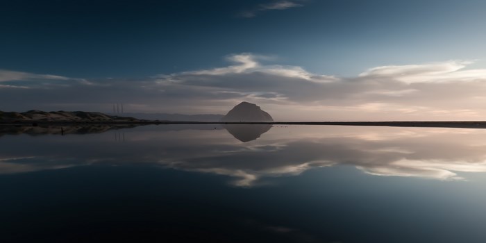 Morro Rock reflection in calm water at sunset