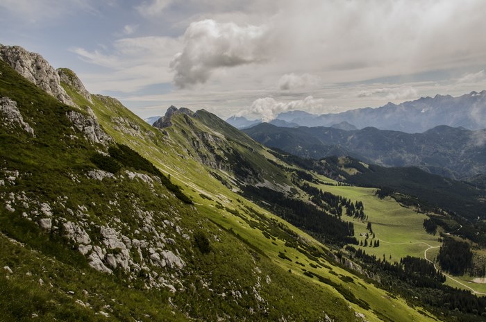 Mountain slope with green valley and distant peaks