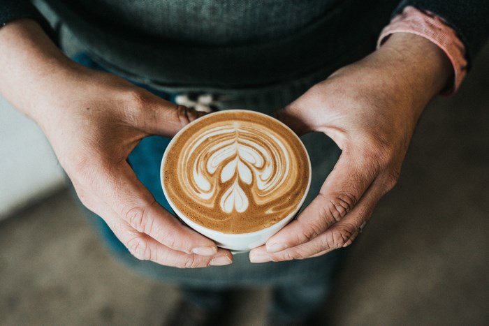Barista holding a latte with intricate latte art