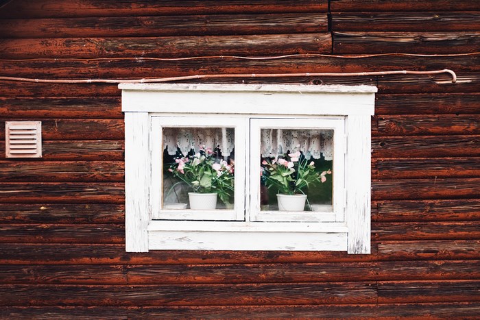 Wooden house with flowers in the window