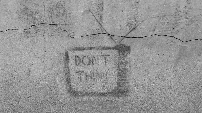 Graffiti on a cracked concrete wall with the words "DON'T THINK"