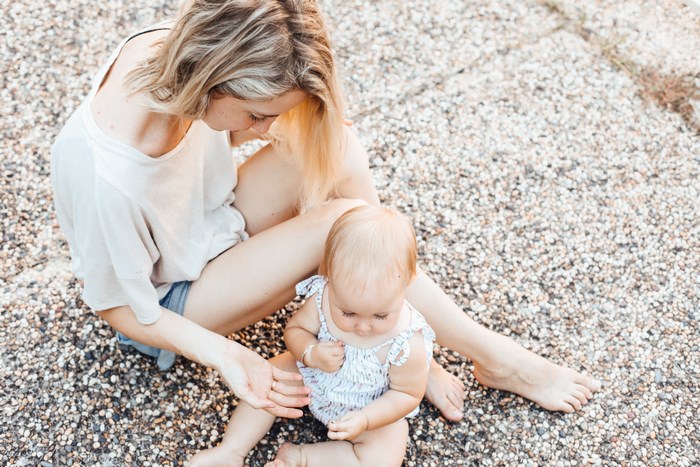 Mom and baby daughter sitting on gravel