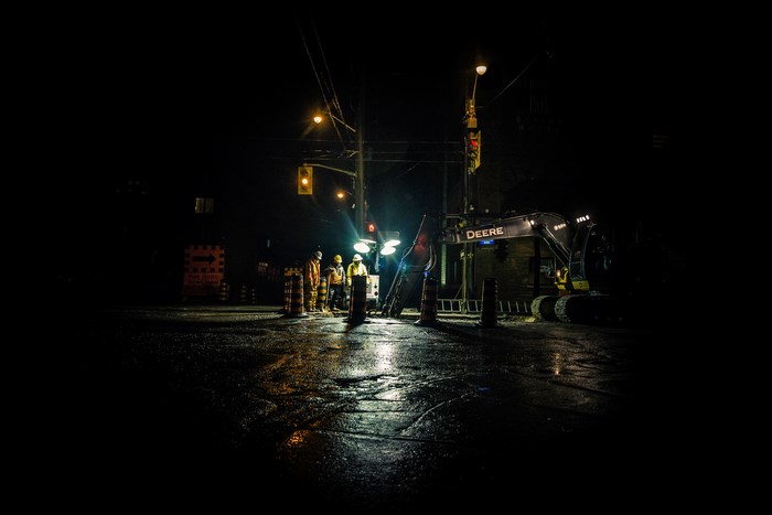 Nighttime construction with John Deere excavator and workers