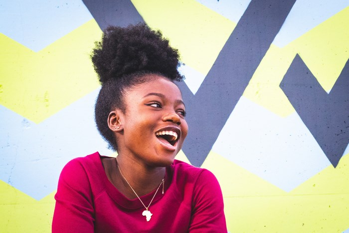 Young Black Woman Laughing in Front of Colorful Wall