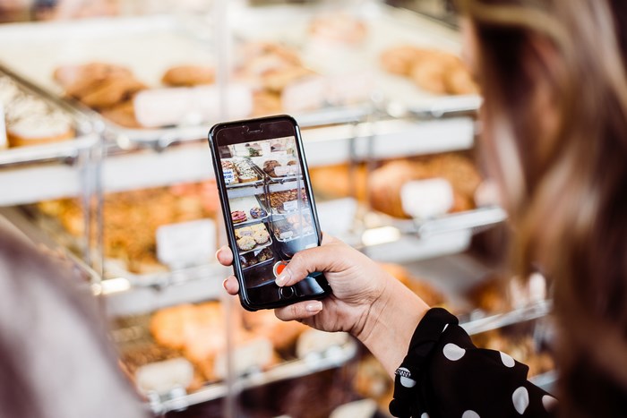 Woman taking a photo of baked goods in a bakery