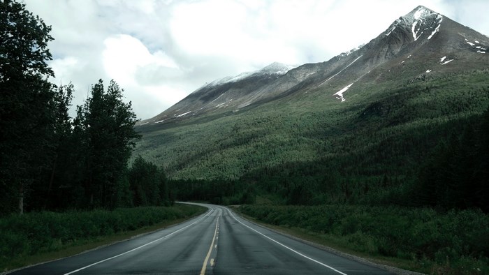 Road through forest to snow-capped mountains