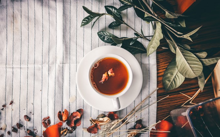 Rose tea in a cup on a striped cloth with leaves