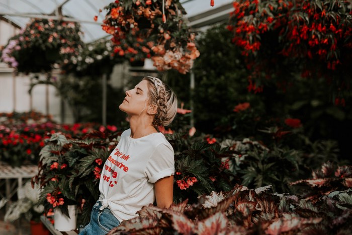 Woman with eyes closed in a greenhouse with flowers