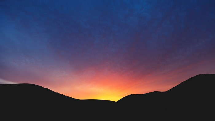 Silhouette of mountains against a vibrant sunset sky