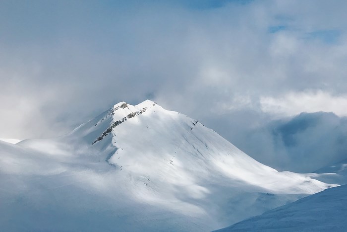Snowy mountain peak under cloudy sky in Gudauri, Georgia