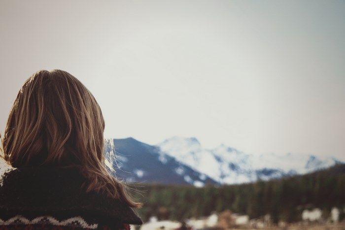 Girl looking at snow-capped mountains and forest