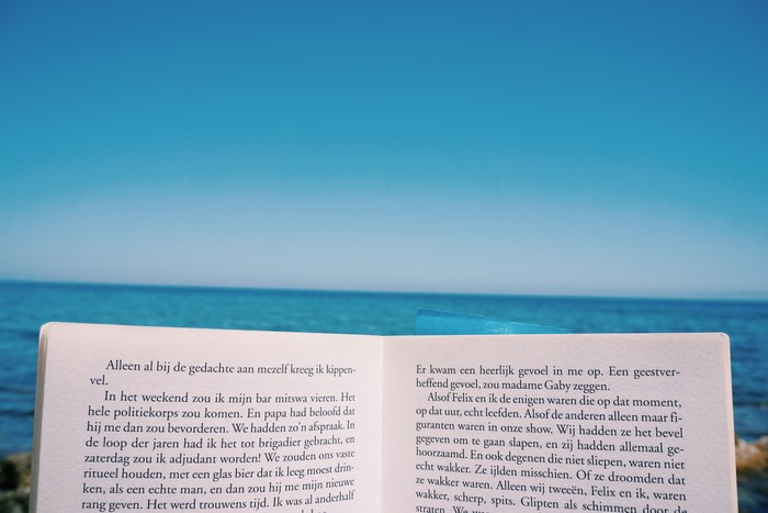Open book on a beach with the sea and sky
