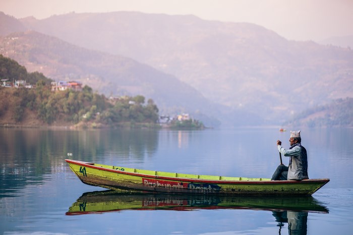 Man rowing a boat on a lake with mountains