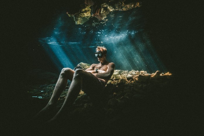 Man in goggles sitting underwater in a cave