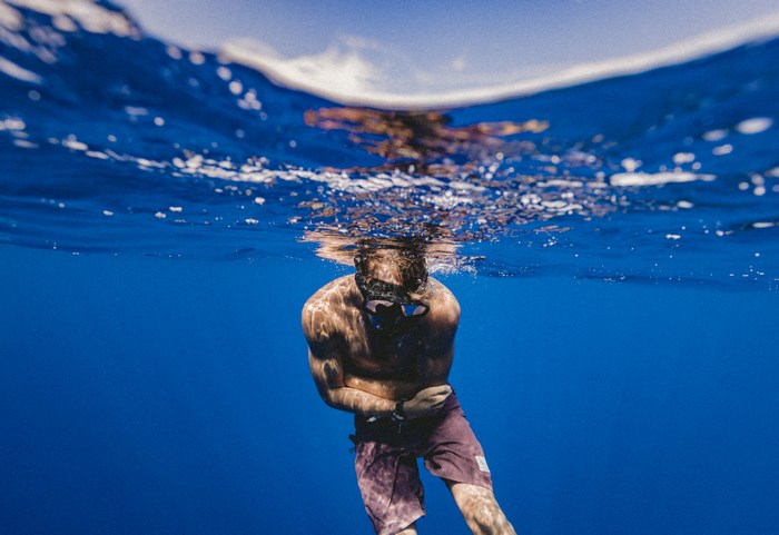 Man snorkeling underwater in blue ocean