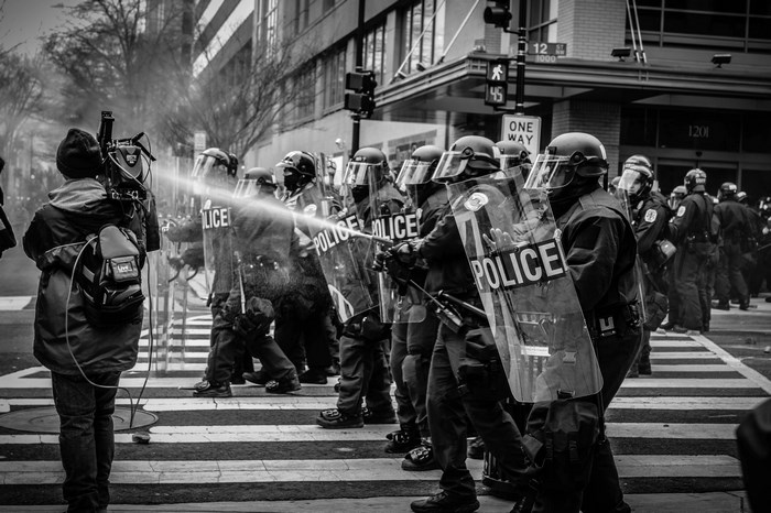 Police officers use water cannon on a journalist during a protest