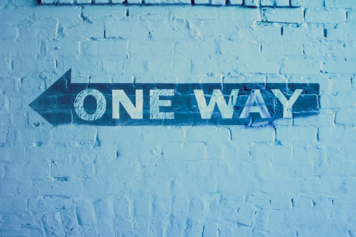 One Way sign painted on a brick wall
