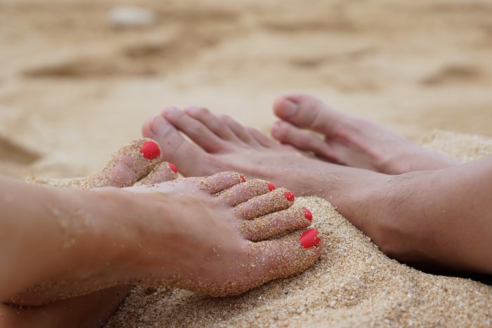 Couple's feet covered in sand on a beach