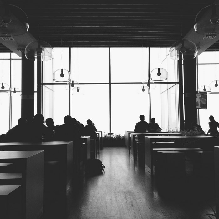 People silhouetted in a modern cafe with large windows