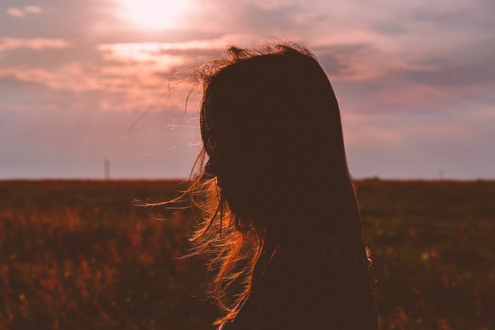 Silhouette of a woman against a sunset sky