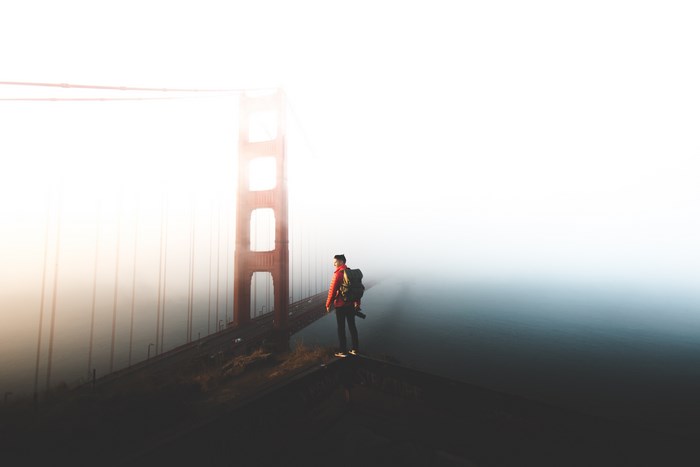 Man with backpack on Golden Gate Bridge in fog
