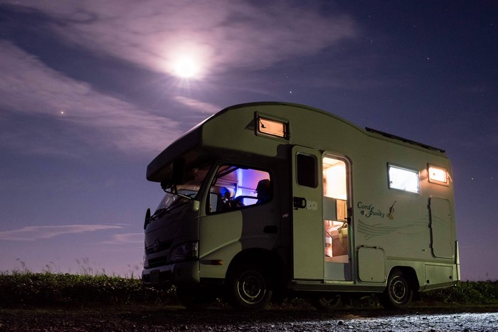 Camper van parked under a starry night sky with moon