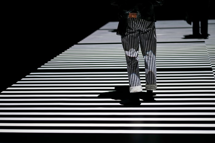 Man in striped trousers on a striped runway