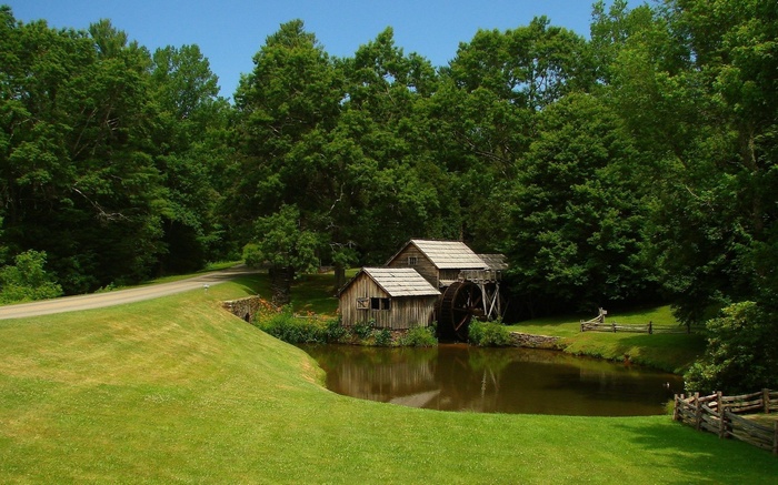 Old water mill by a pond surrounded by trees