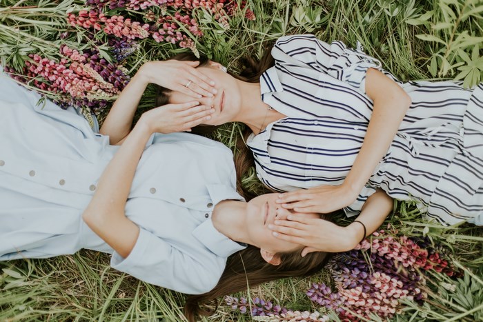 Two women lying in grass with flowers