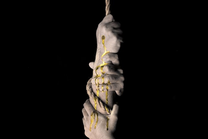 Hands holding a rope with gold paint