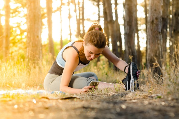 Young woman stretching in a sunlit forest
