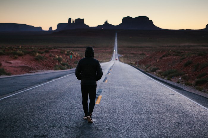 Man walking on open road in Monument Valley at sunset