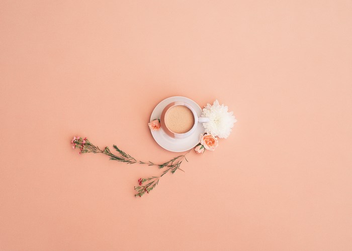 Flat lay of coffee cup with flowers and greenery