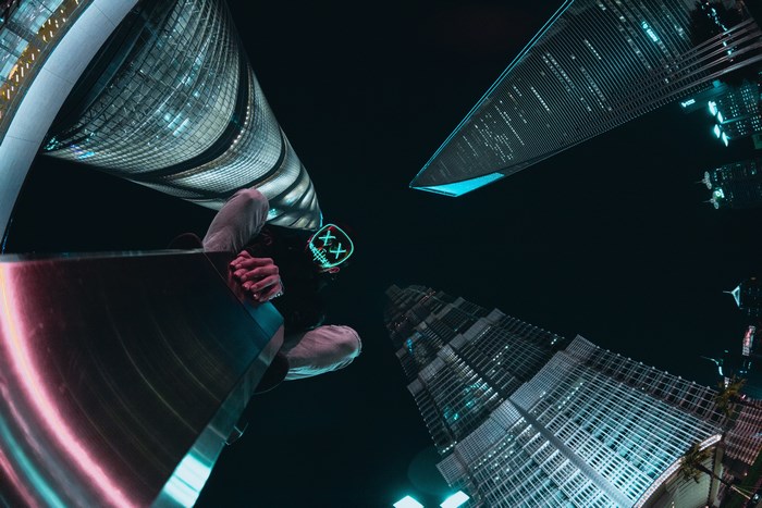 Person in mask looking up at Shanghai skyscrapers at night
