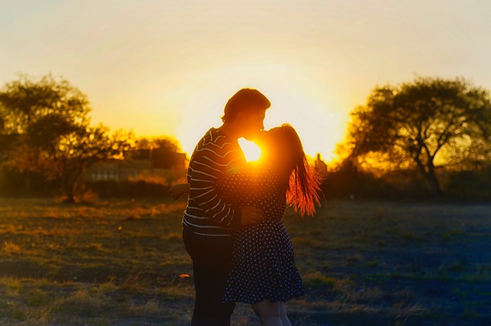 Couple kissing at sunset in a field