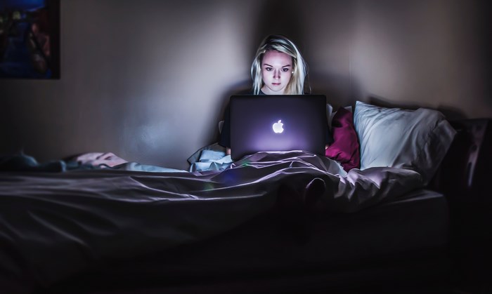 Woman working on a laptop in bed at night