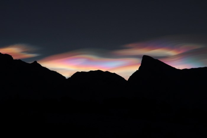Iridescent clouds over silhouetted mountains in Lofoten Islands