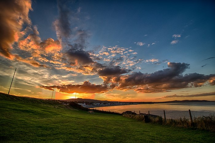 Sunset over a coastal town with grassland and sea