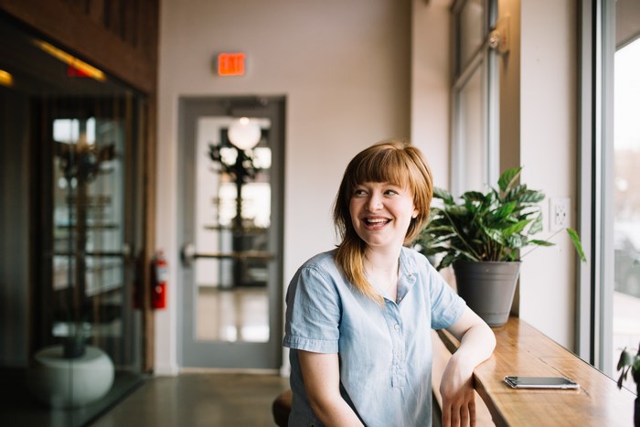 Woman smiling by a window with a potted plant