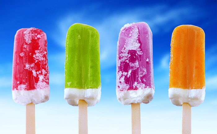 Four colorful popsicles on sticks against a blue sky