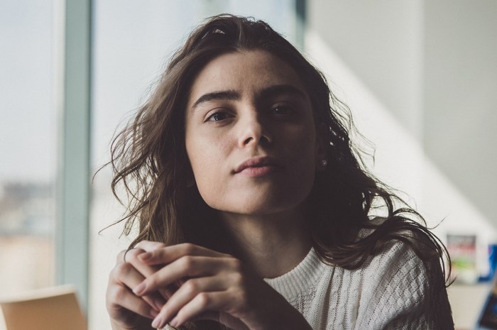 Young woman with brown hair in a white sweater