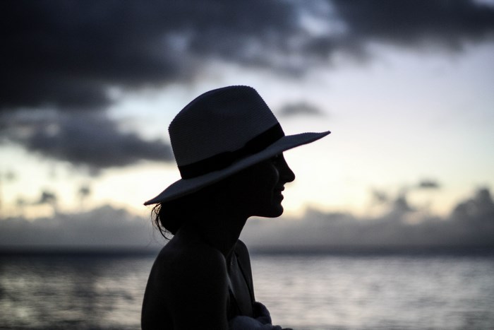 Woman in hat at sunset over the ocean