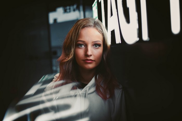 Woman in hoodie with neon lights in background