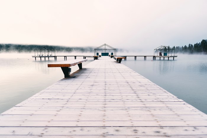 Wooden dock with benches on a misty lake in winter