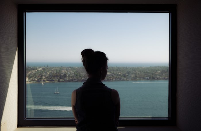 Woman looking out a window at the sea