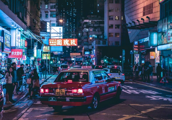 Red taxi on a busy city street at night